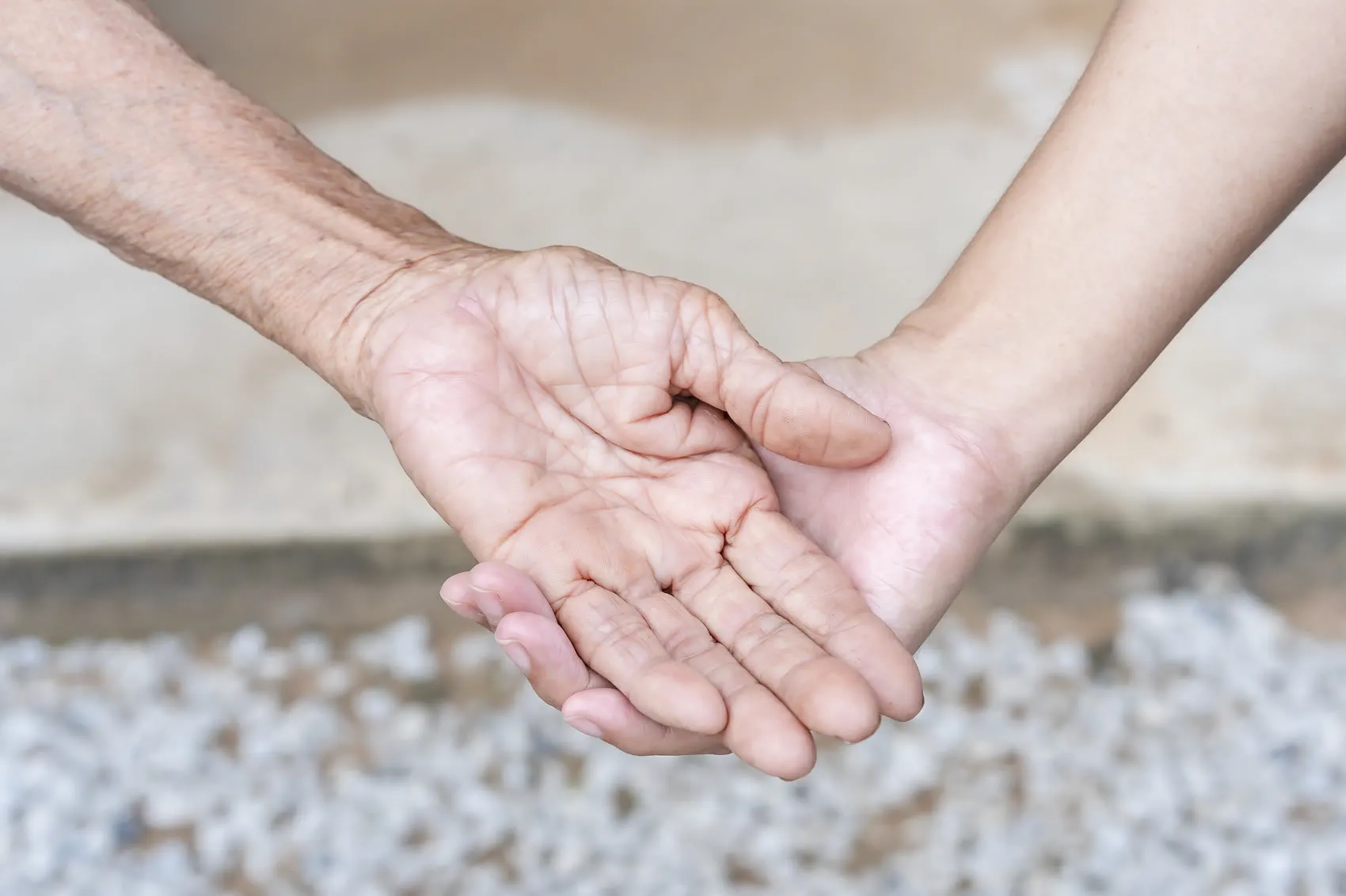 Mãos de uma pessoa idosa apoiadas nas mãos da cuidadora